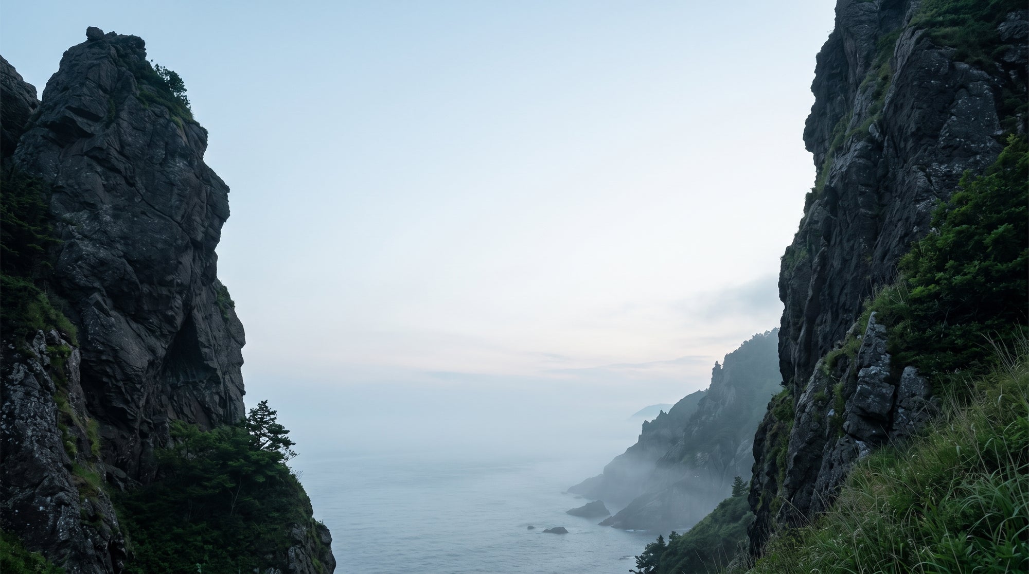 A wide, peaceful coastal landscape at dusk with dark cliffs on the sides and a clear sky in the center.
