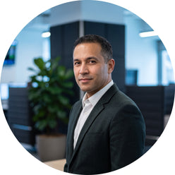 A professional portrait of a male trader from Prop Desk Chicago, set against a blurred, dark office background with subtle bl